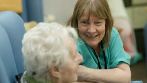 Caregiver in green scrubs assisting an elderly resident