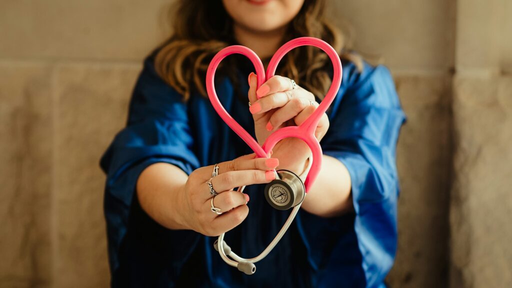 Nurse in scrubs holding a heart-shaped stethoscope