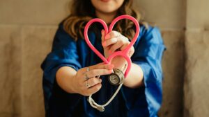 Nurse in scrubs holding a heart-shaped stethoscope