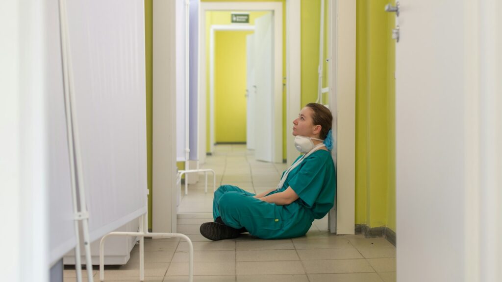 Healthcare worker sitting alone in a hallway