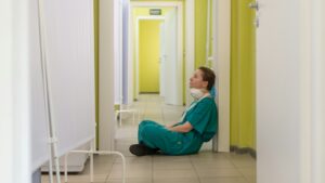 Healthcare worker sitting alone in a hallway